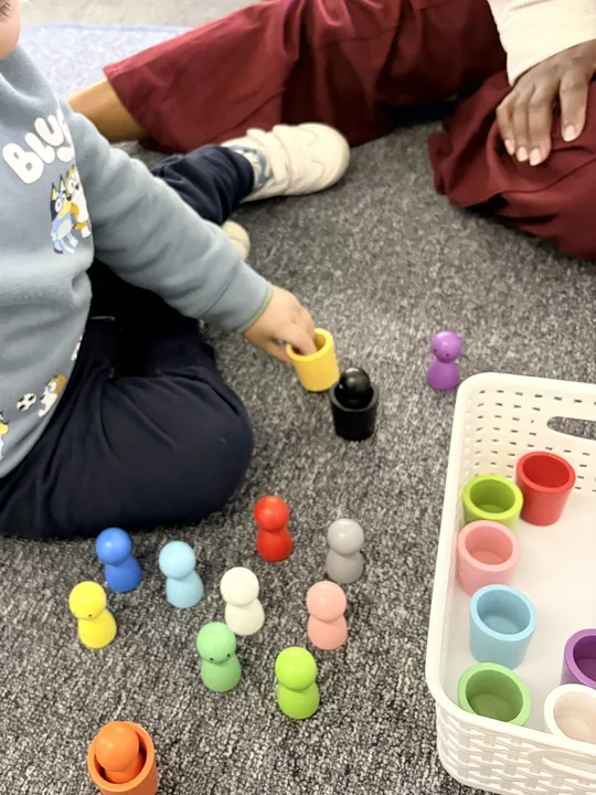 A caregiver sitting alongside a child during a sorting activity
